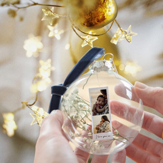 A glass bauble filled with dried flowers and photos